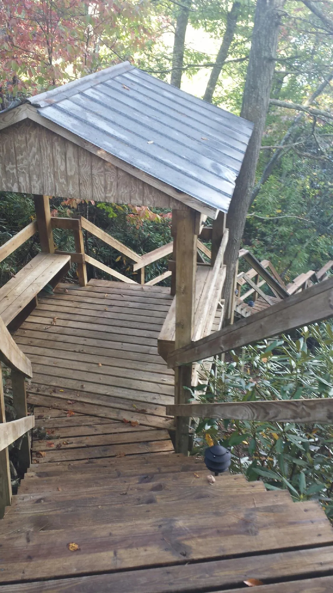 Metal roofed shelter over wooden steps on a wooded walkway — Skylight Repair & Installation work by our crew in Little Falls